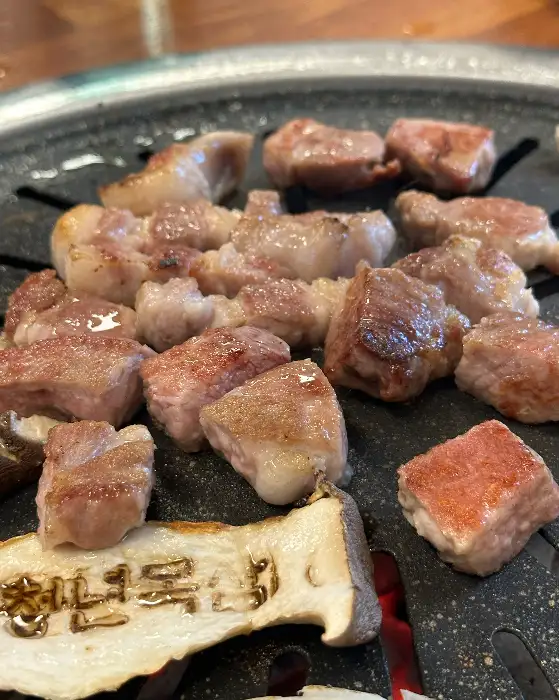 구워진 삼겹살 조각들이 불판 위에 올려져 있다.