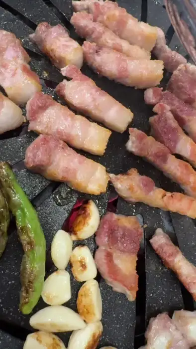잘 구워지고 있는 두툼한 삼겹살과 꽈리고추, 마늘