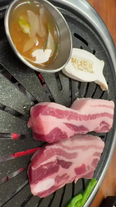 불판 위에 올려진 두툼한 삼겹살 덩어리