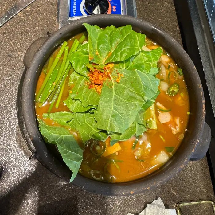 비빔냉면 위로 채 썬 오이, 계란 지단, 그리고 붉은 양념이 보인다.