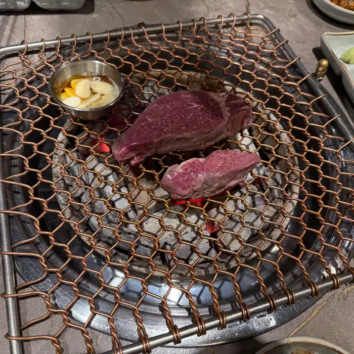숯불 위에서 맛있게 구워지고 있는 한우일번지X규이치의 한우 구이