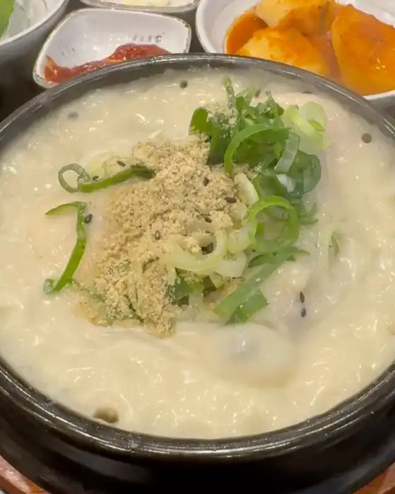 들깨 삼계탕의 고소하고 진한 국물 위로 갓 썰어낸 파와 튀긴 깨가 뿌려져 먹음직스러운 모습