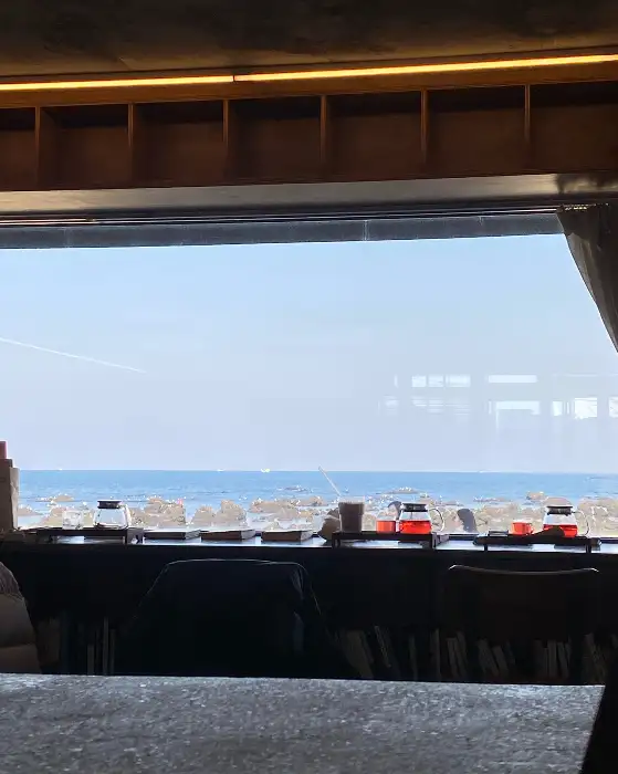 창가 테이블에 놓인 커피잔과 붉은 빛깔의 액체가 담긴 병들