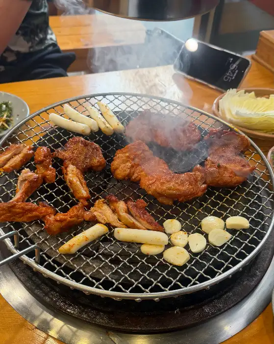 숯불 위에서 익고 있는 닭갈비와 떡, 마늘 등