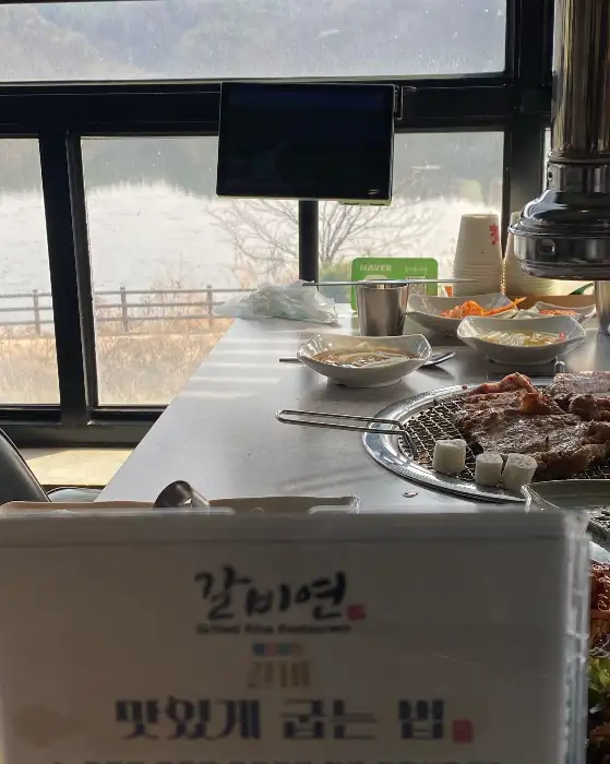 창가 테이블에 놓인 숯불, 고기, 그리고 밑반찬들