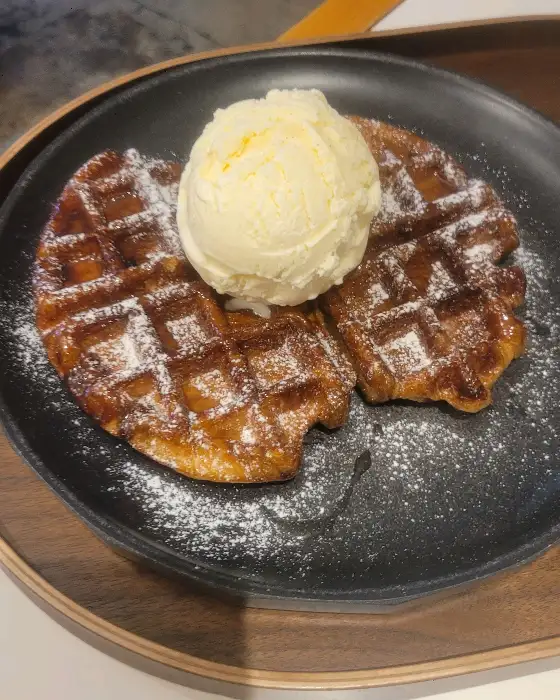 가루 설탕이 뿌려진 두 개의 와플 위에 아이스크림이 듬뿍 올라간 모습