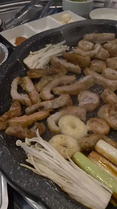 돌판 위에서 노릇하게 익어가는 막창과 함께 팽이버섯, 대파, 단호박이 가지런히 놓여 있습니다.