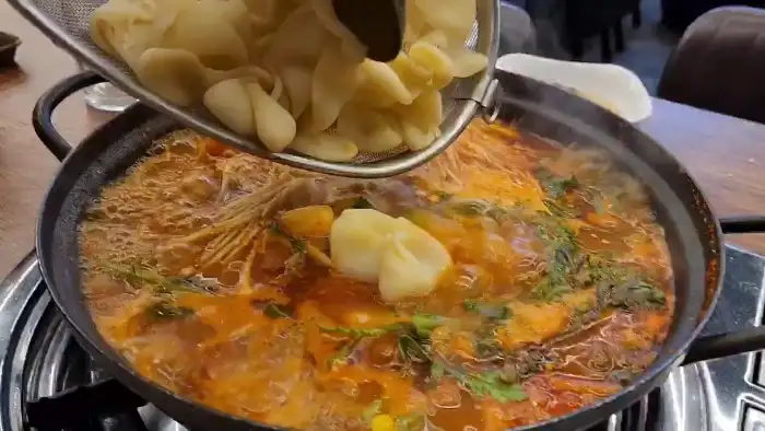 뜨거운 육수에 수제비와 라면 사리를 넣는 모습