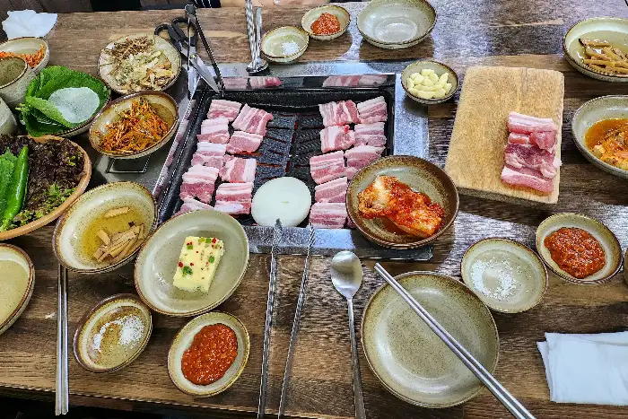 맛있게 구워지고 있는 삼겹살과 곁들임 음식들