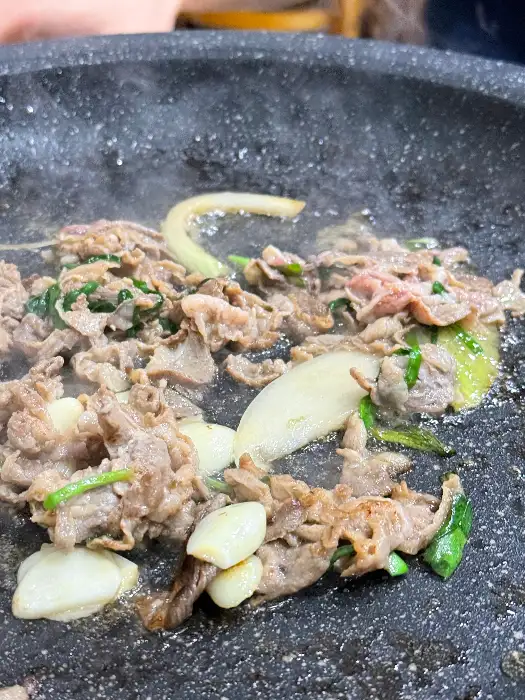 오리불고기가 익으면서 나오는 기름과 채소, 마늘이 어우러진 모습