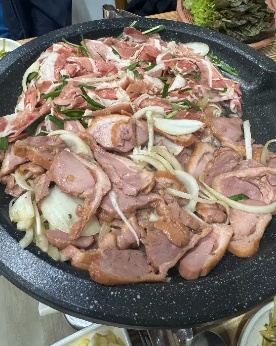 불판 위에 익어가는 오리 불고기와 양파, 파채의 모습