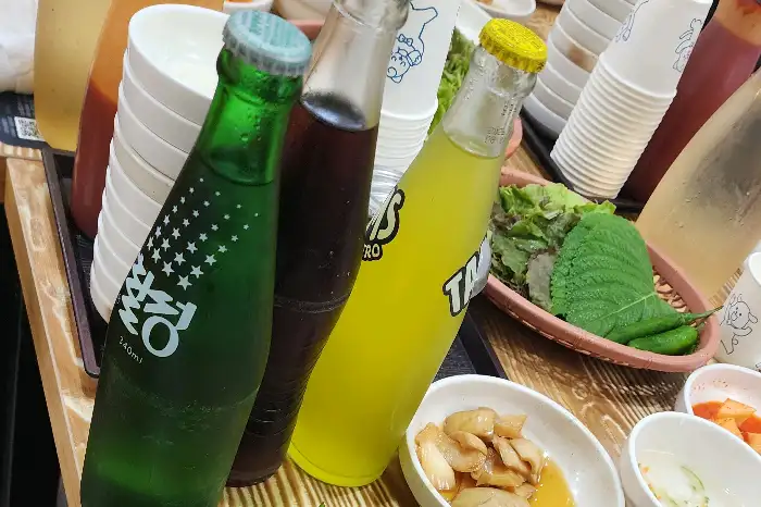 상큼한 탄산음료 병들과 신선한 쌈채소, 고추의 모습