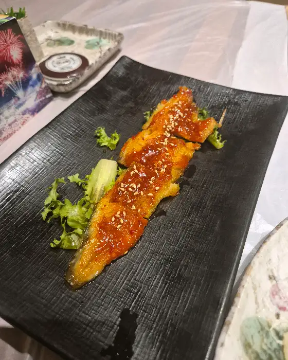 검은색 접시에 담긴 윤기 나는 황태구이 요리