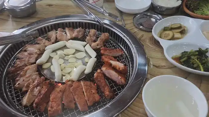 숯불 위에서 익어가는 닭갈비와 곁들임 메뉴