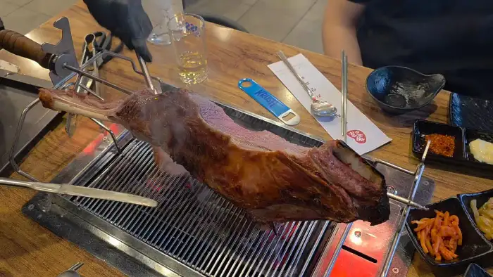 거대한 양다리가 숯불 위에서 회전하며 익어가는 모습