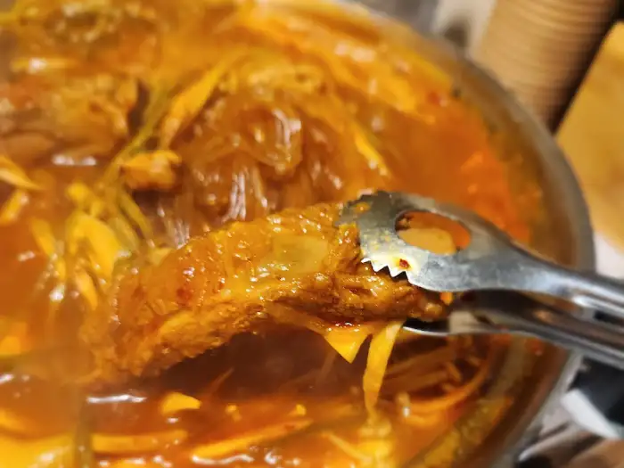 집게로 집어 올린 등갈비와 함께 보이는 묵은지