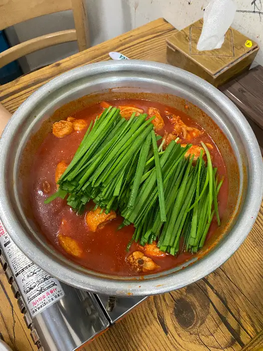 김이 나는 닭볶음탕 냄비와 젓가락, 그리고 냅킨이 놓여 있는 테이블 모습