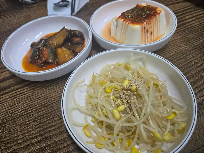 숙주나물, 가지볶음, 순두부 요리 등 다양한 밑반찬들이 담긴 그릇들