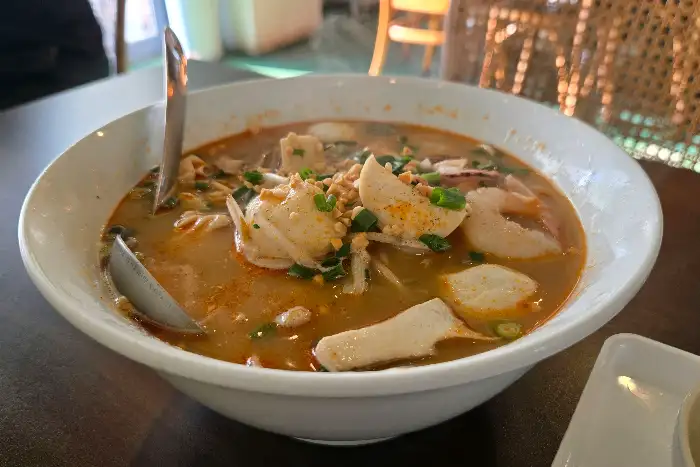 푸릇푸릇한 쏨땀 클로즈업 사진. 신선한 채소와 토마토, 땅콩이 보입니다.