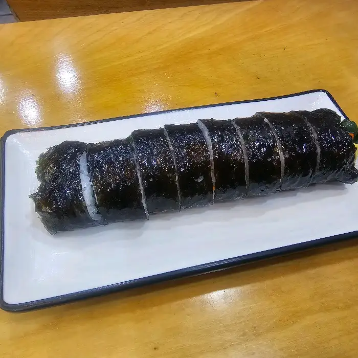 김밥 한 줄이 깔끔하게 썰려 접시에 담겨 있습니다.