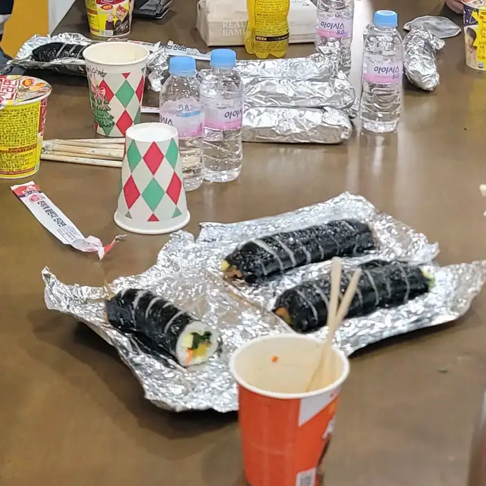 테이블 위에 김밥, 물병, 컵 등이 놓여 있는 모습입니다.
