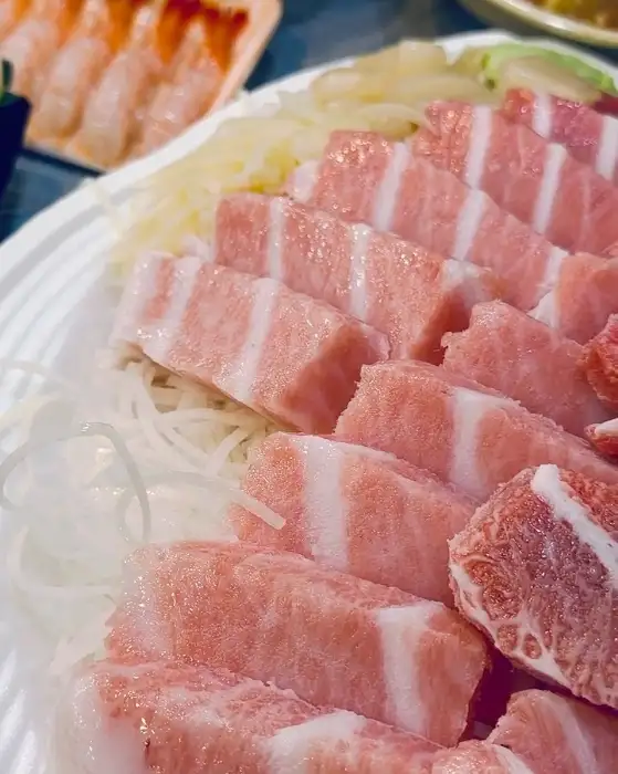 붉은 살과 하얀 지방층이 교차하는 선명한 패턴을 가진 참치회 조각들. 얇게 썰린 회가 먹음직스럽게 놓여 있다.