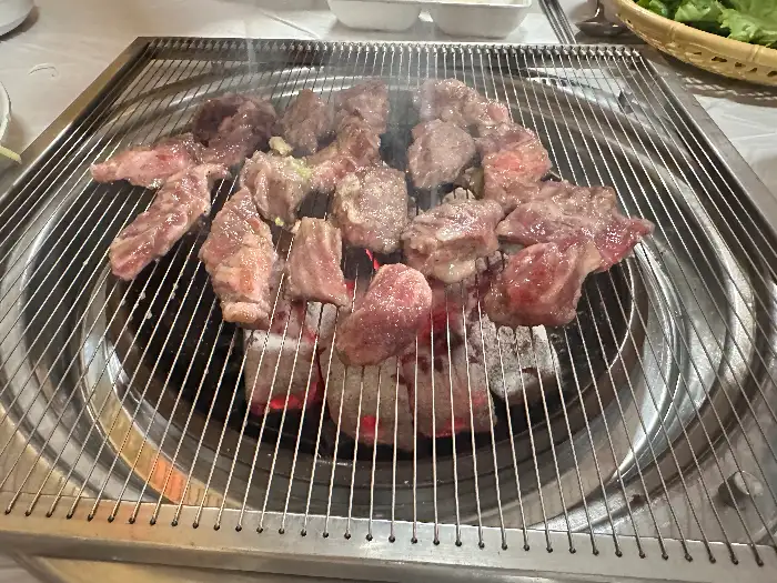 숯불 위에서 구워지고 있는 소갈비 여러 조각