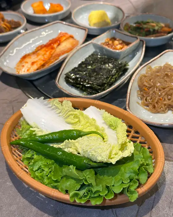 다양한 밑반찬과 신선한 채소가 차려진 한우일번지X규이치 식사 상차림