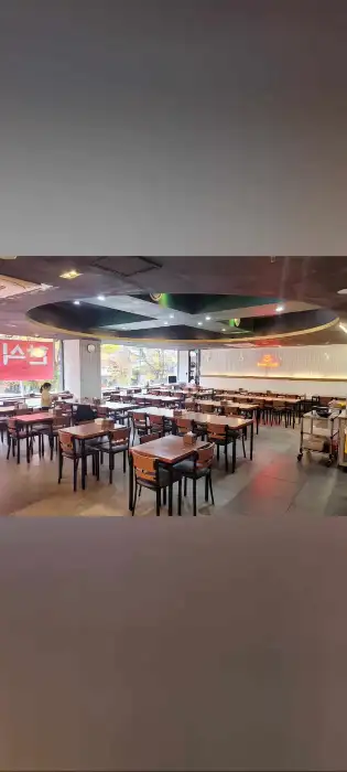 식당 내부 풍경. 다양한 테이블이 놓여 있고, 사람들이 식사하고 있는 모습.